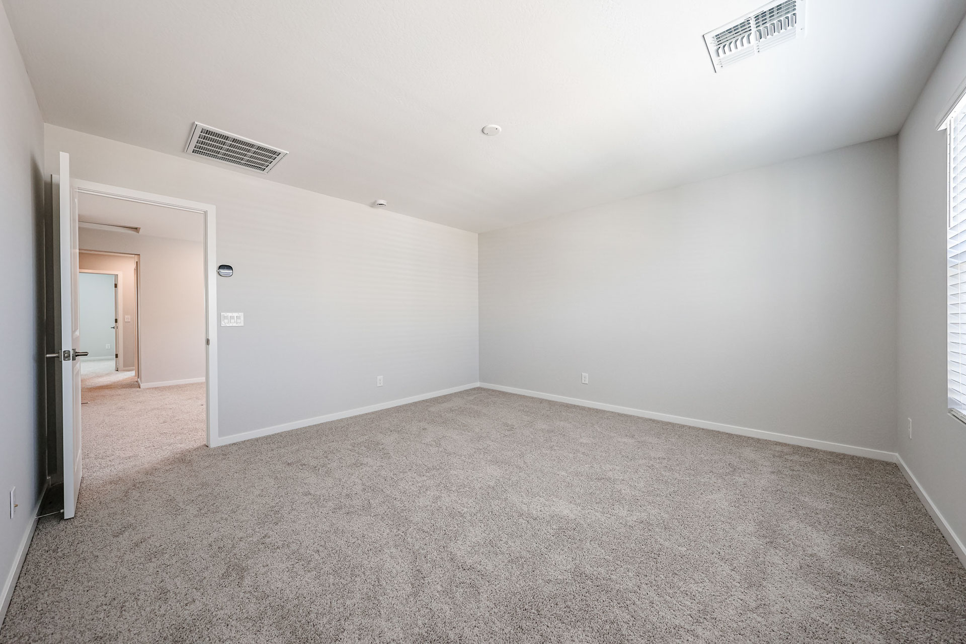 A room with a carpet and a vent.