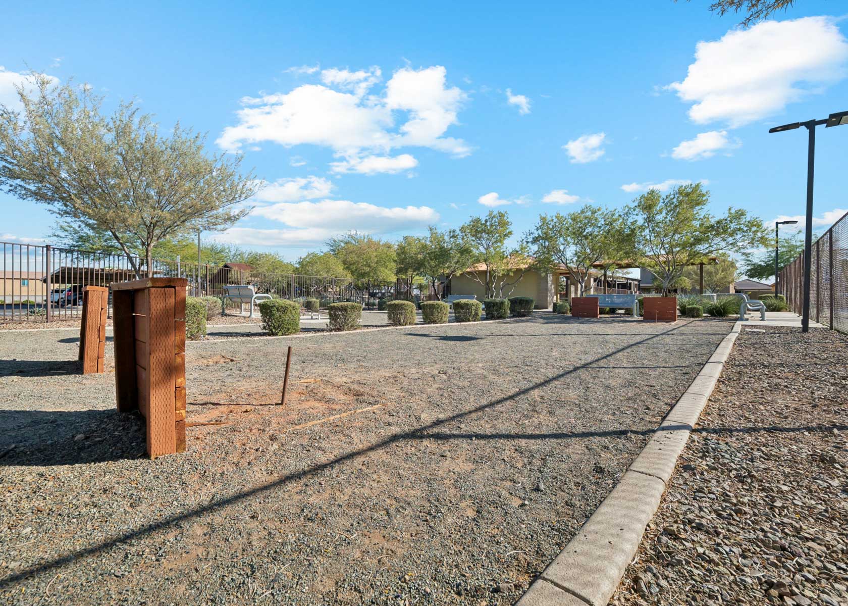 A paved area with trees and houses in the background.