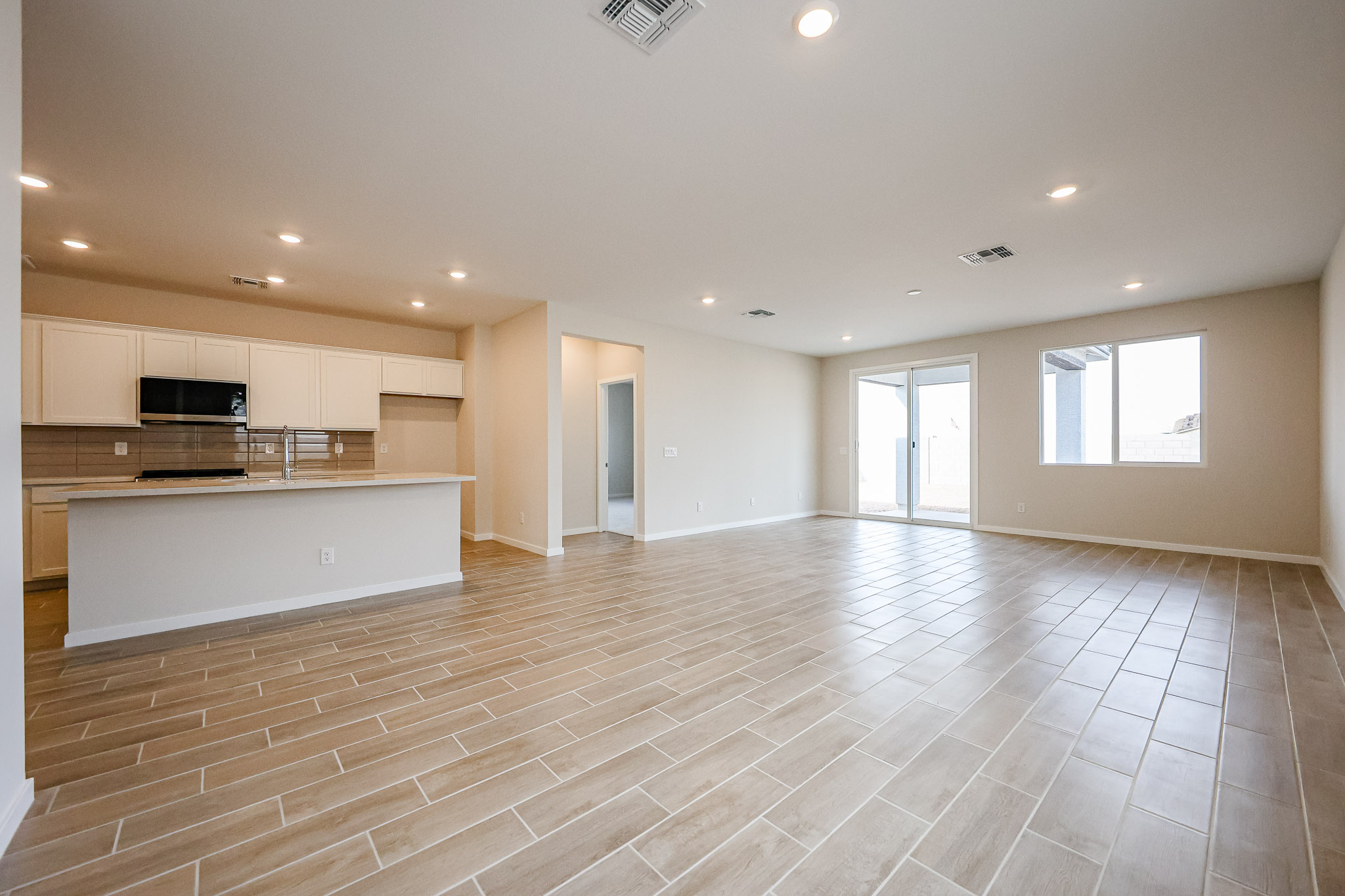 A large empty room with a wood floor and white cabinets.
