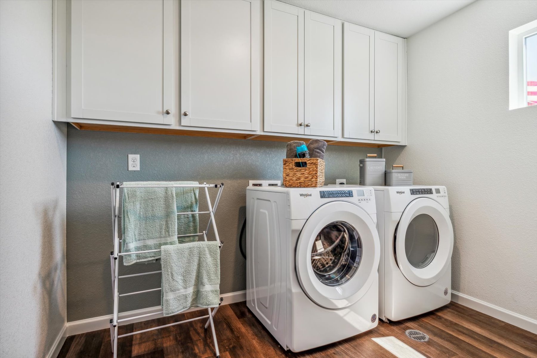 A laundry room with white cabinets.