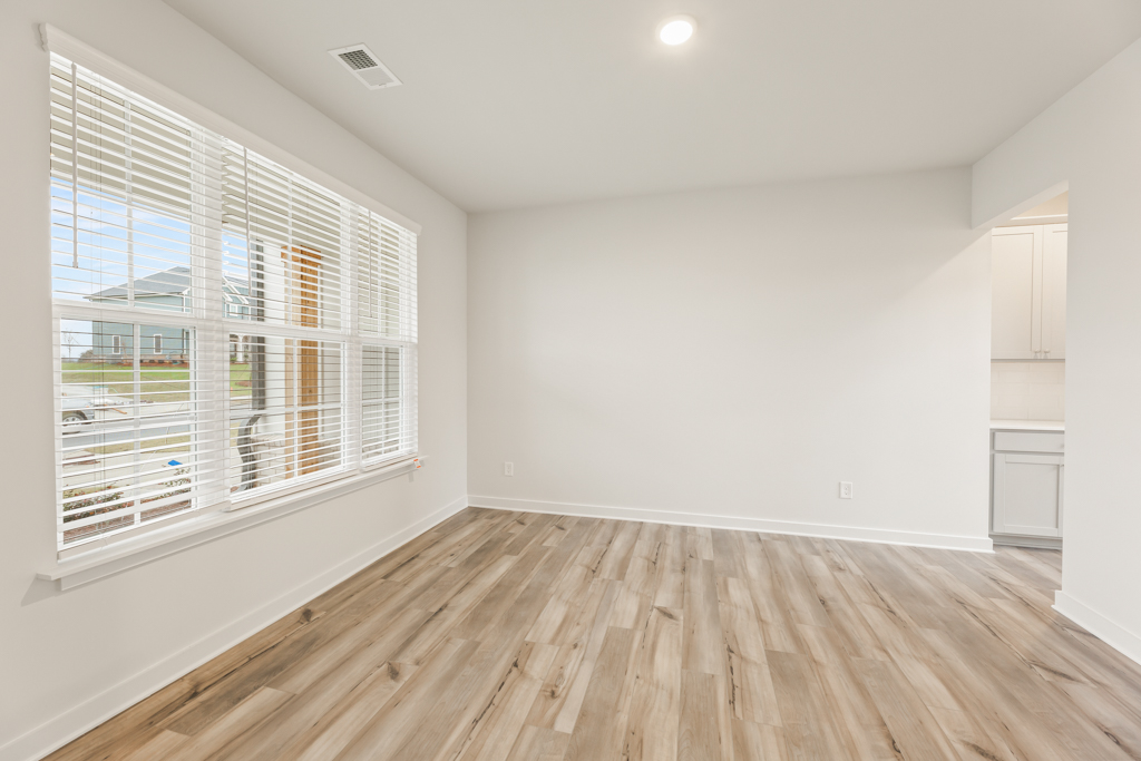 A room with a wood floor and a window with blinds.