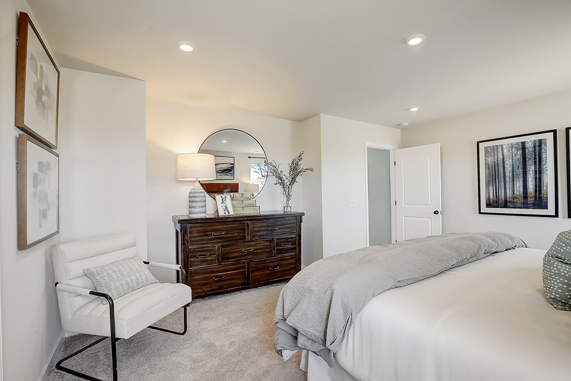 A bedroom with a bed and a chair.