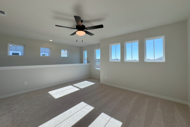 A room with a ceiling fan and windows.