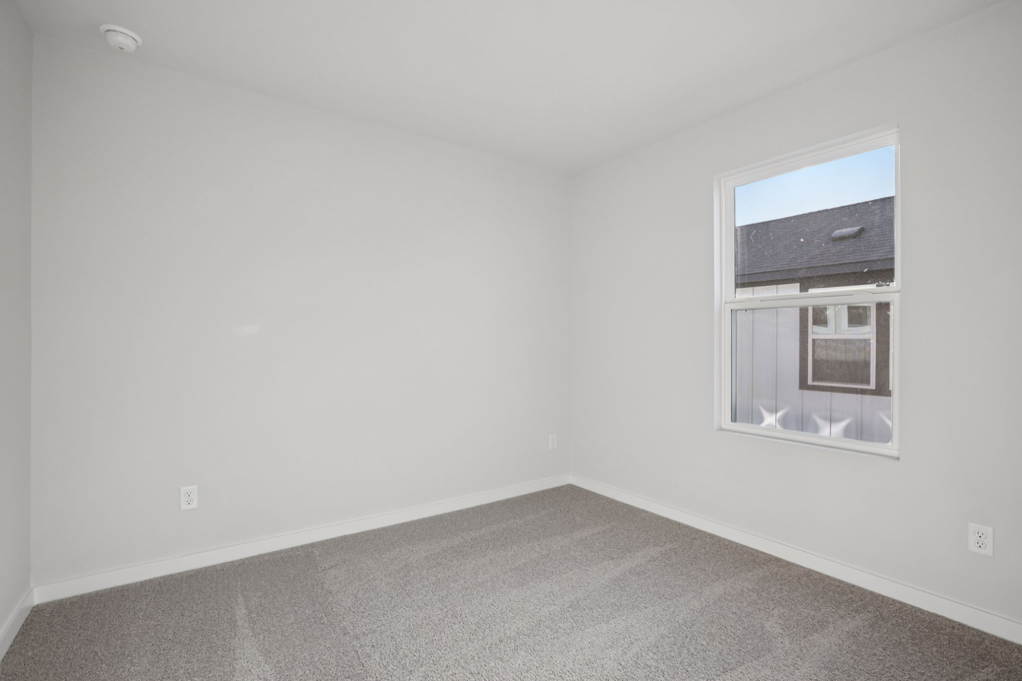 A room with a window and a white wall.