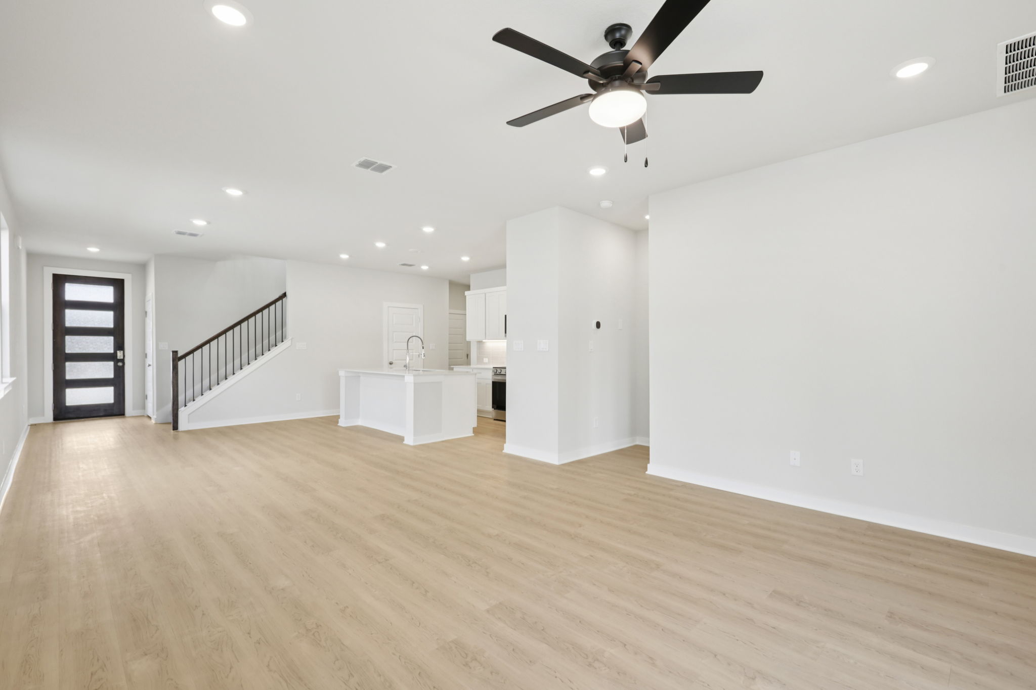 A large empty room with a wood floor and a ceiling fan.