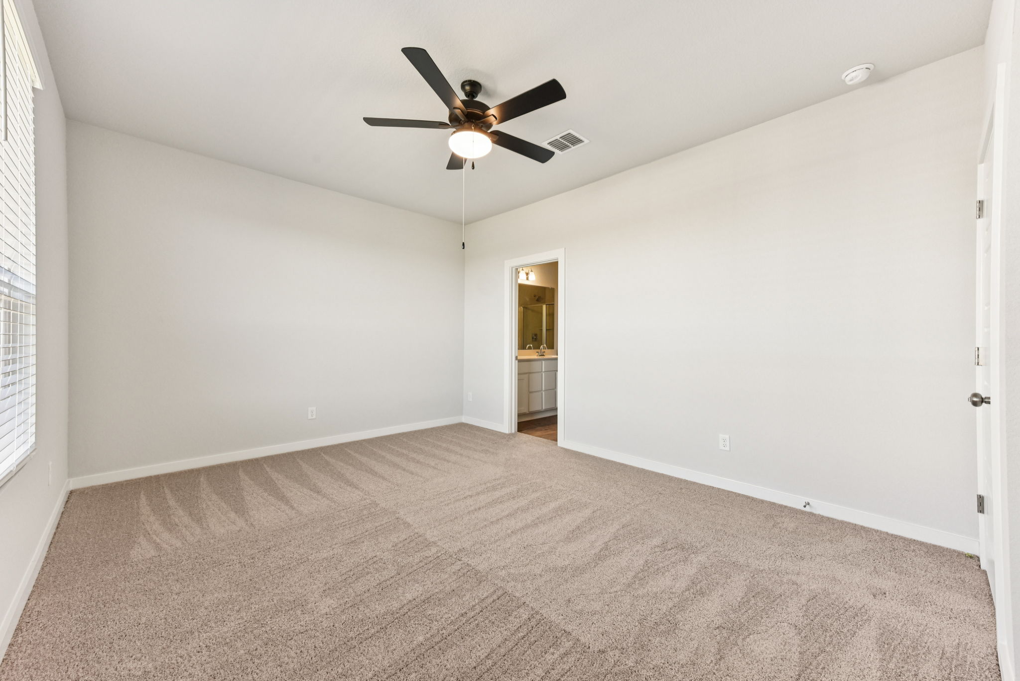 A room with a ceiling fan and carpet.