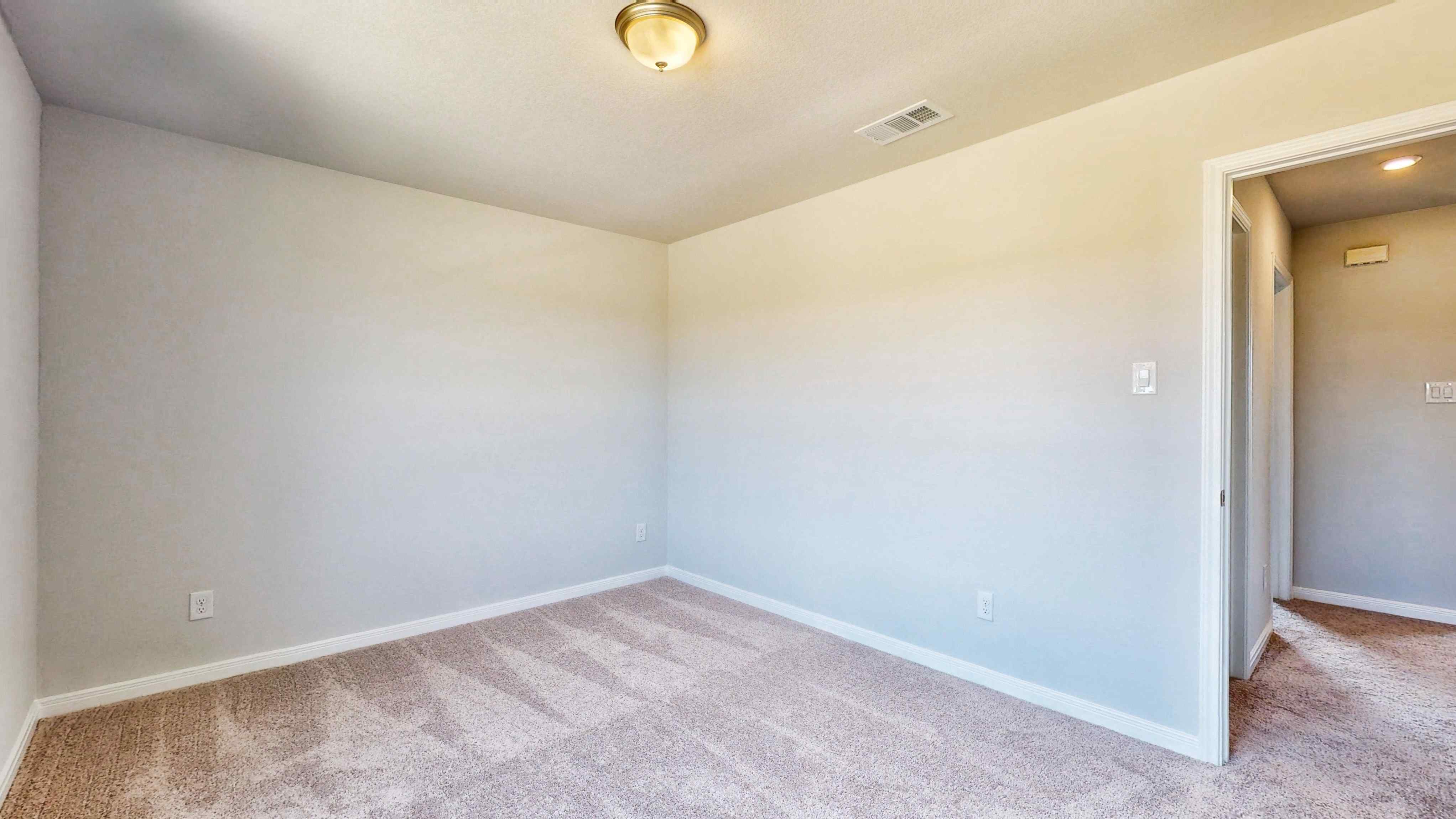 A room with a carpet and a light on the wall.