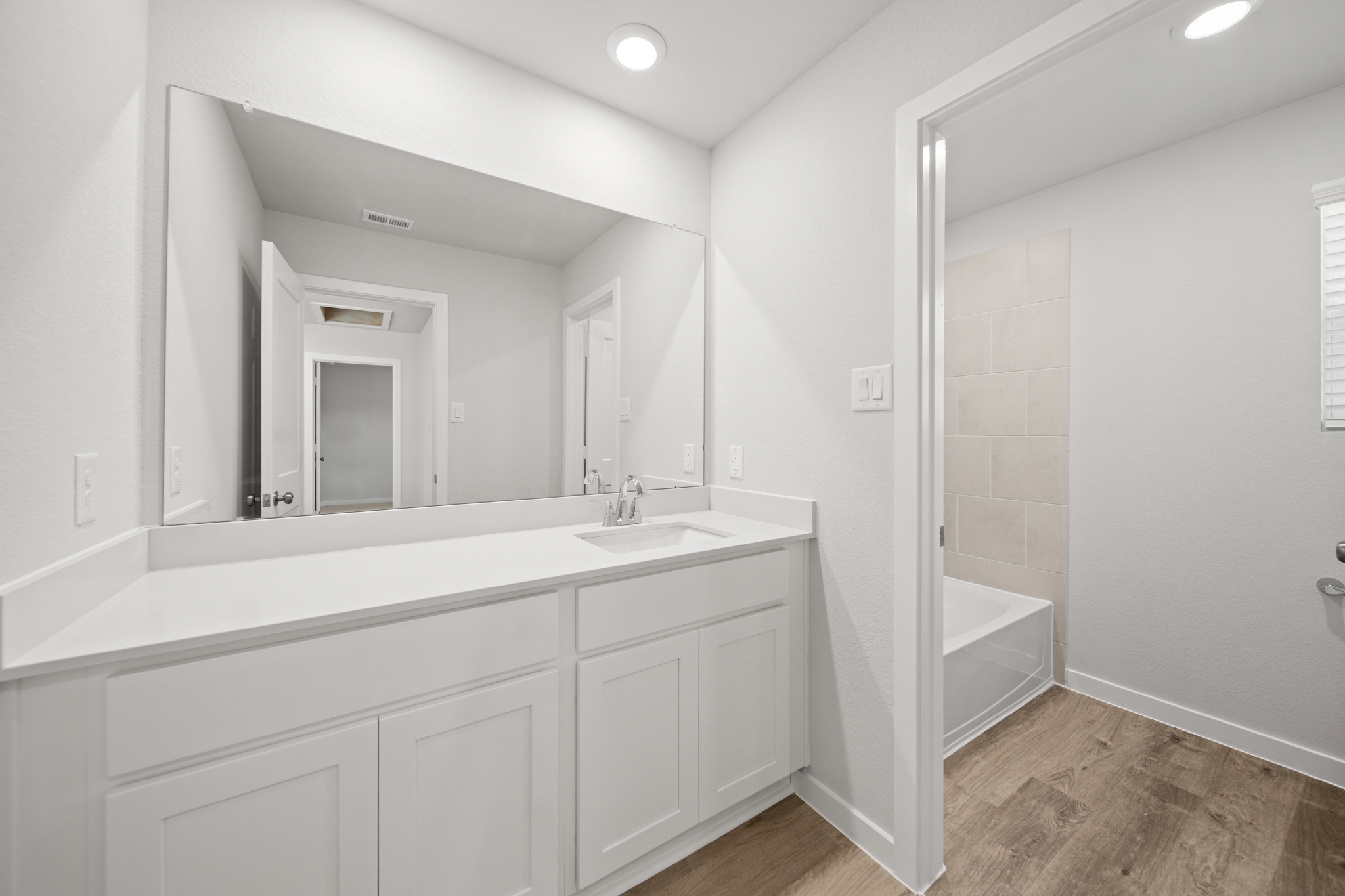 A bathroom with a tub sink and mirror.