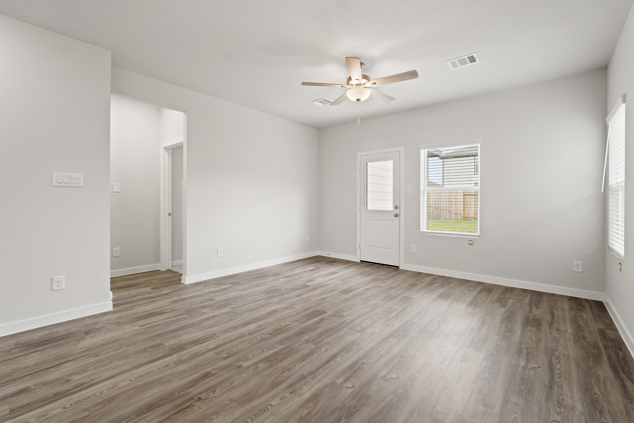 A room with a wood floor and a ceiling fan.