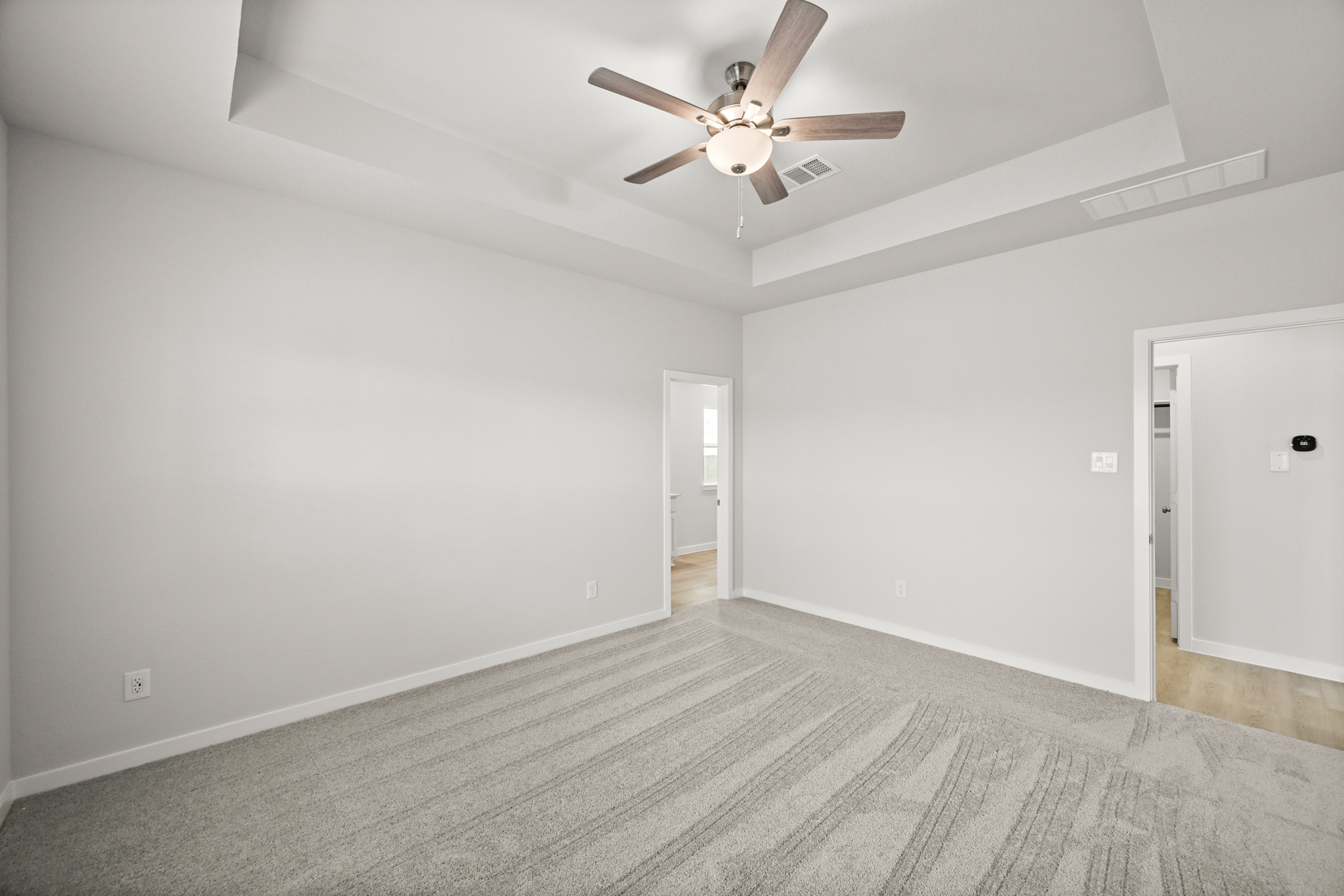 A room with a ceiling fan and a door.