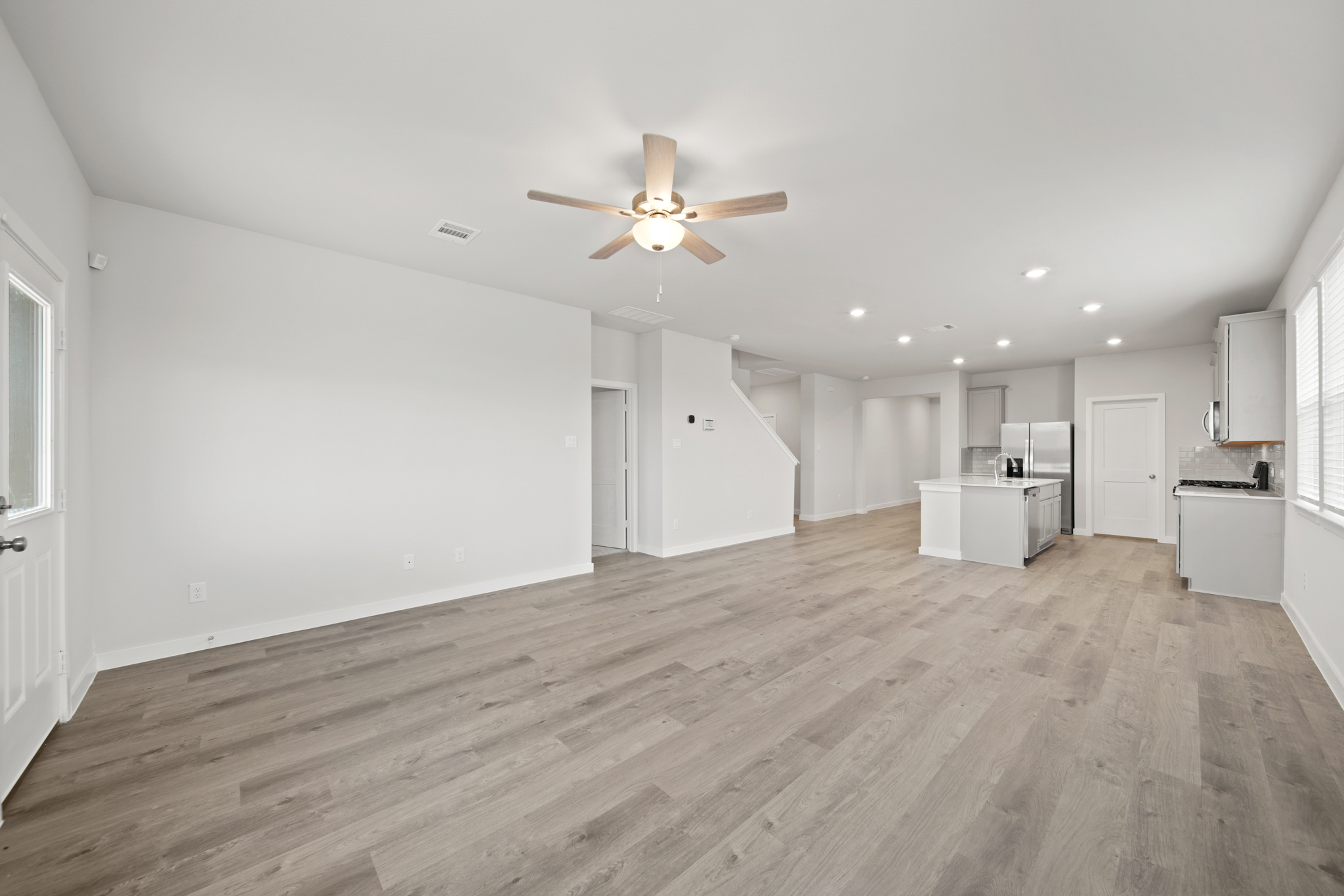A large empty room with a wood floor and a ceiling fan.