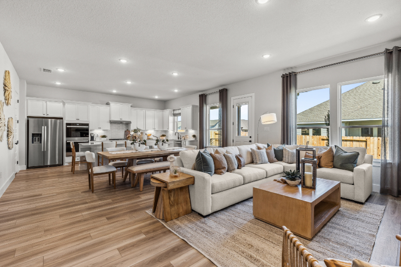 A large living room with a large white couch and a dining table.