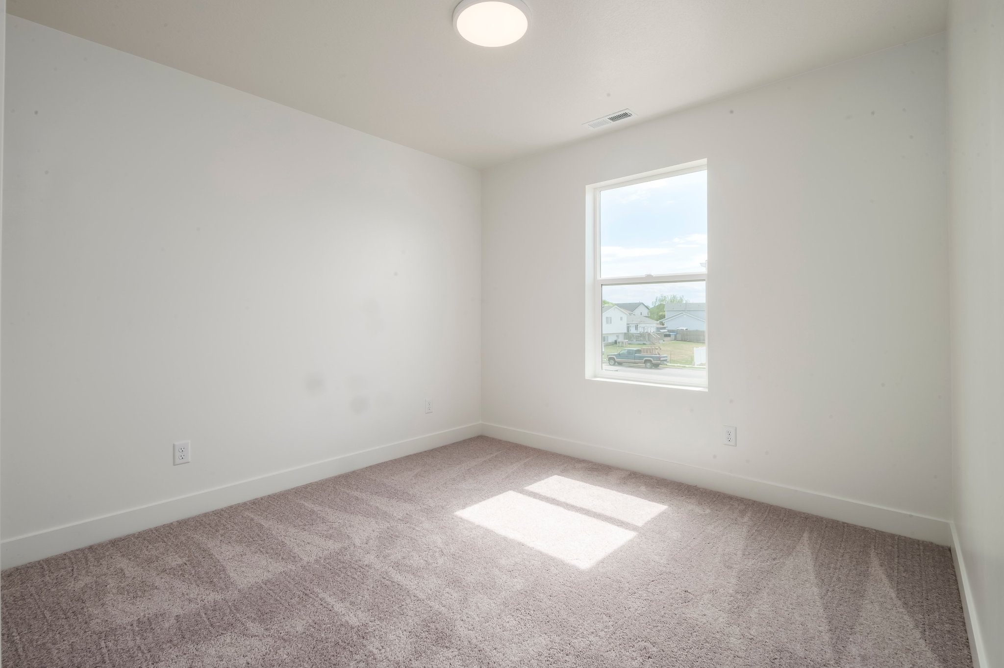 A room with a window and a rug.